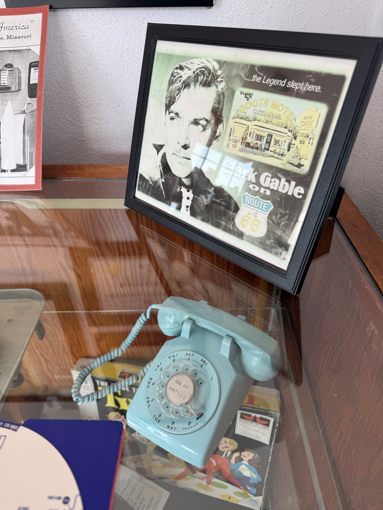 Gerahmtes Clark-Gable-Motiv und altes Wählscheibentelefon in einer Vitrine