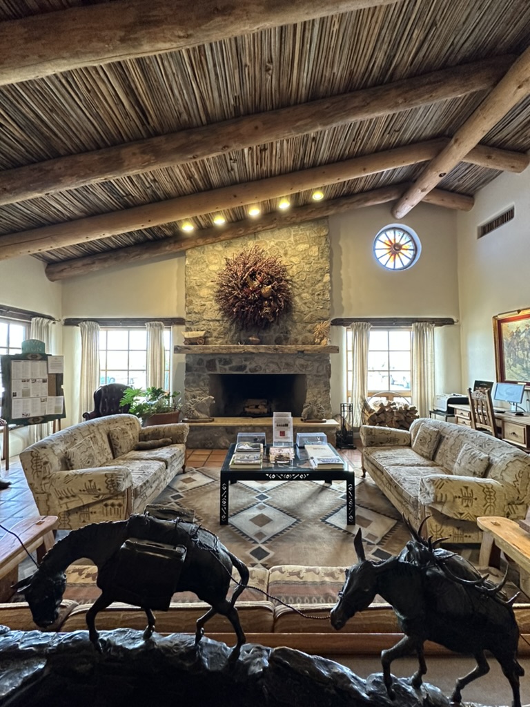 Lobby einer Ranch mit Kamin, Holzbalken und Bronzefiguren