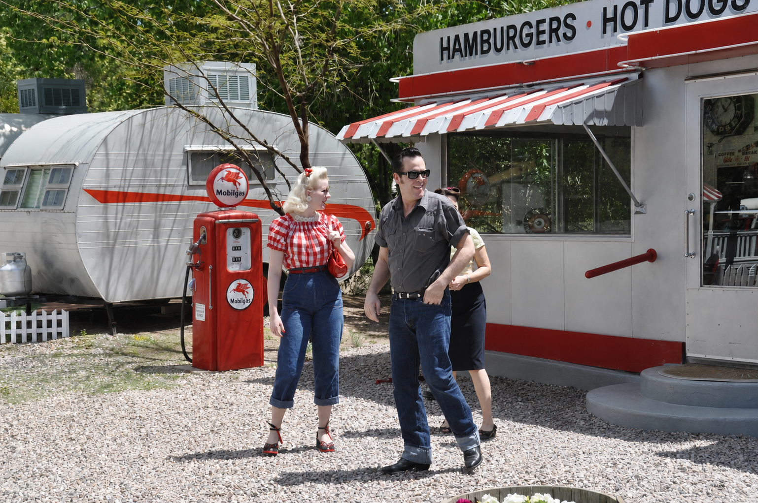 Rockabilly-Paar vor Vintage-Wohnwagen, Mobilgas-Zapfsäule und Diner im Shady Dell in Bisbee, Arizona
