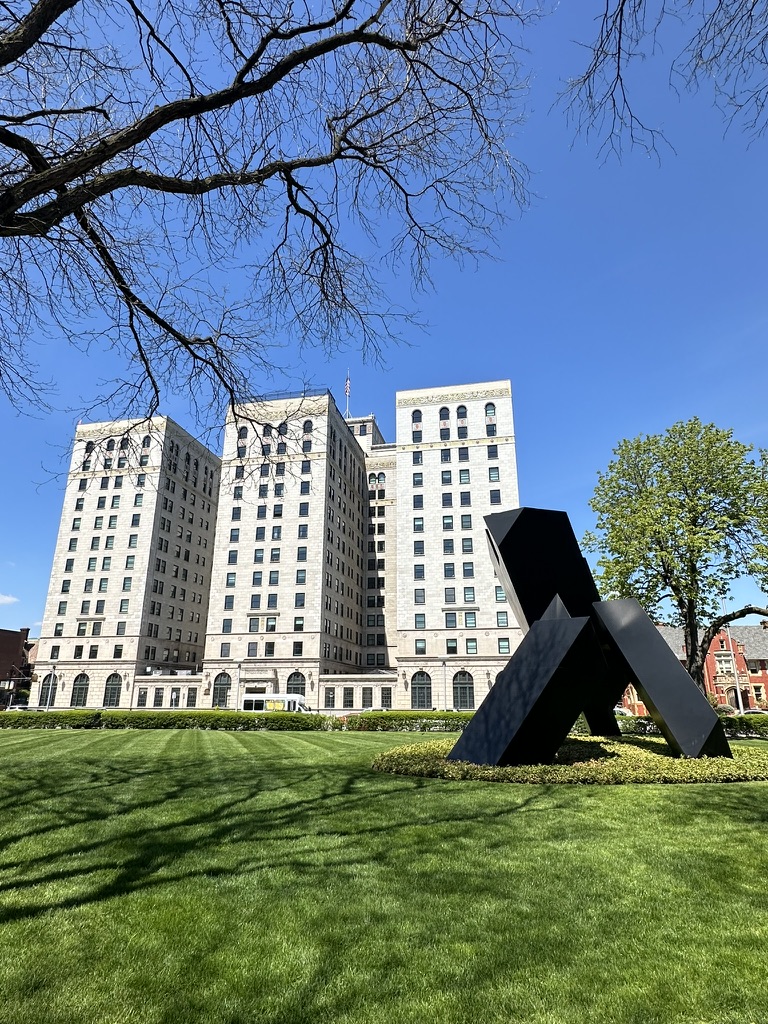 Schwarze Stahlskulptur auf dem Rasen vor einem hellen Hochhaus in Midtown