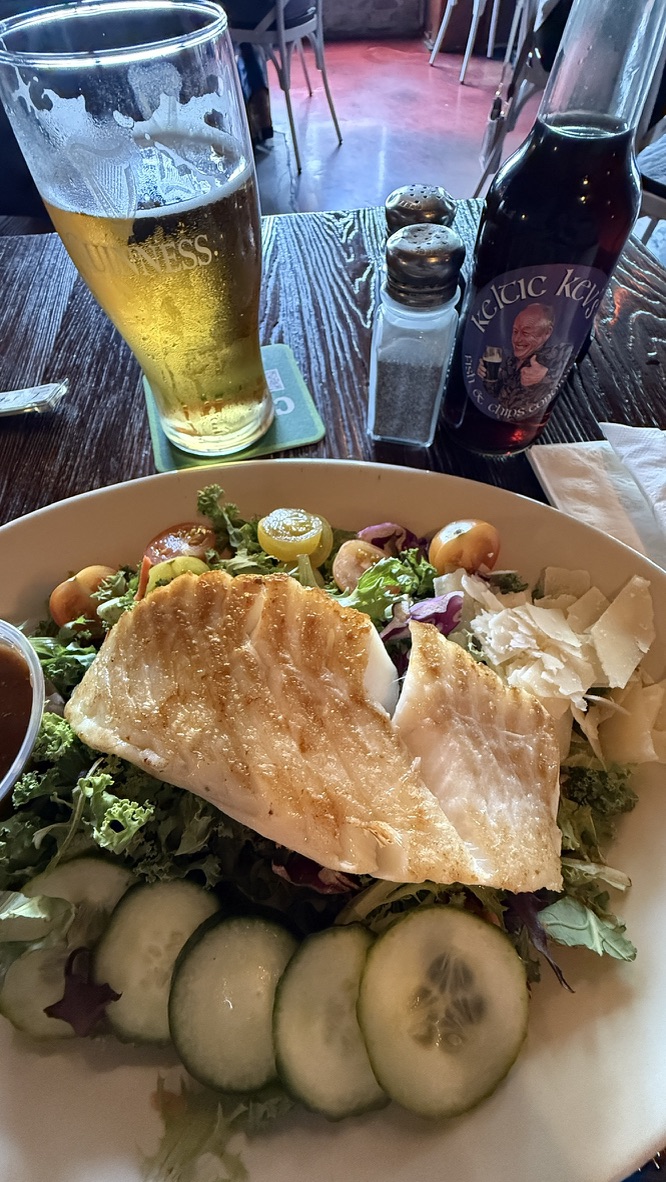 Gebratener Fisch auf Salat mit einem Glas Bier