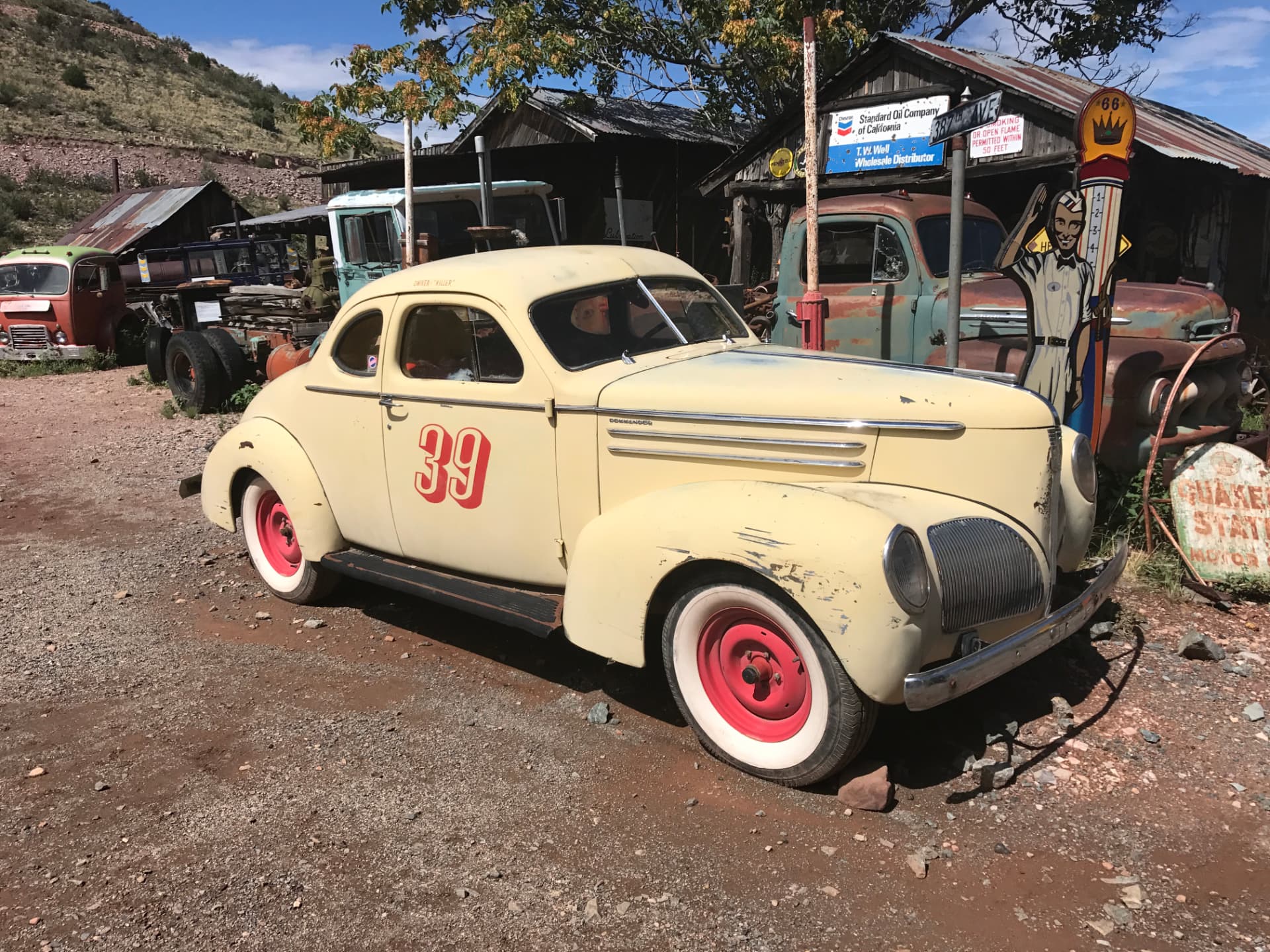 Gelber Oldtimer mit roter Startnummer 39 vor alten Trucks und Blechschildern in der Gold King Mine Ghost Town bei Jerome