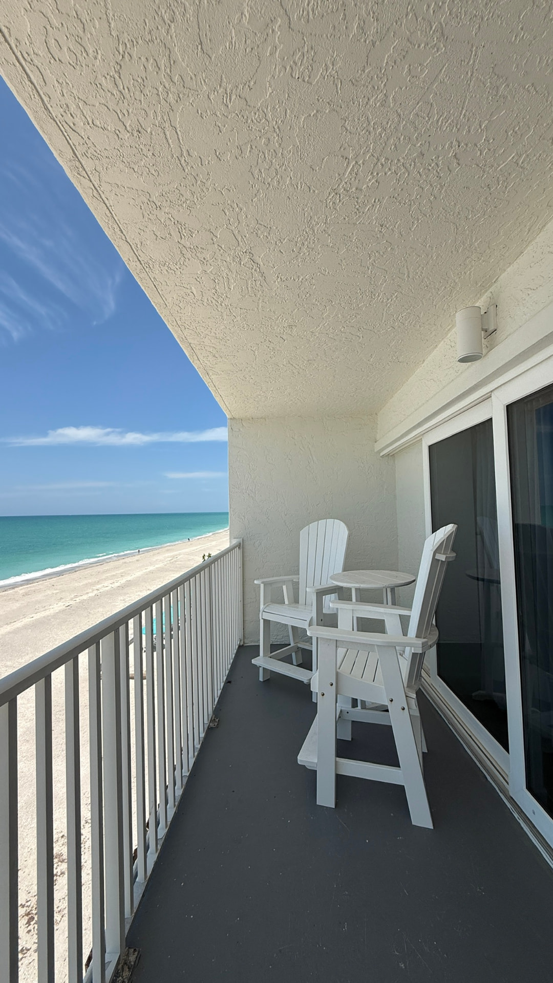 Balkon mit weißen Stühlen und Blick auf Strand und Golf