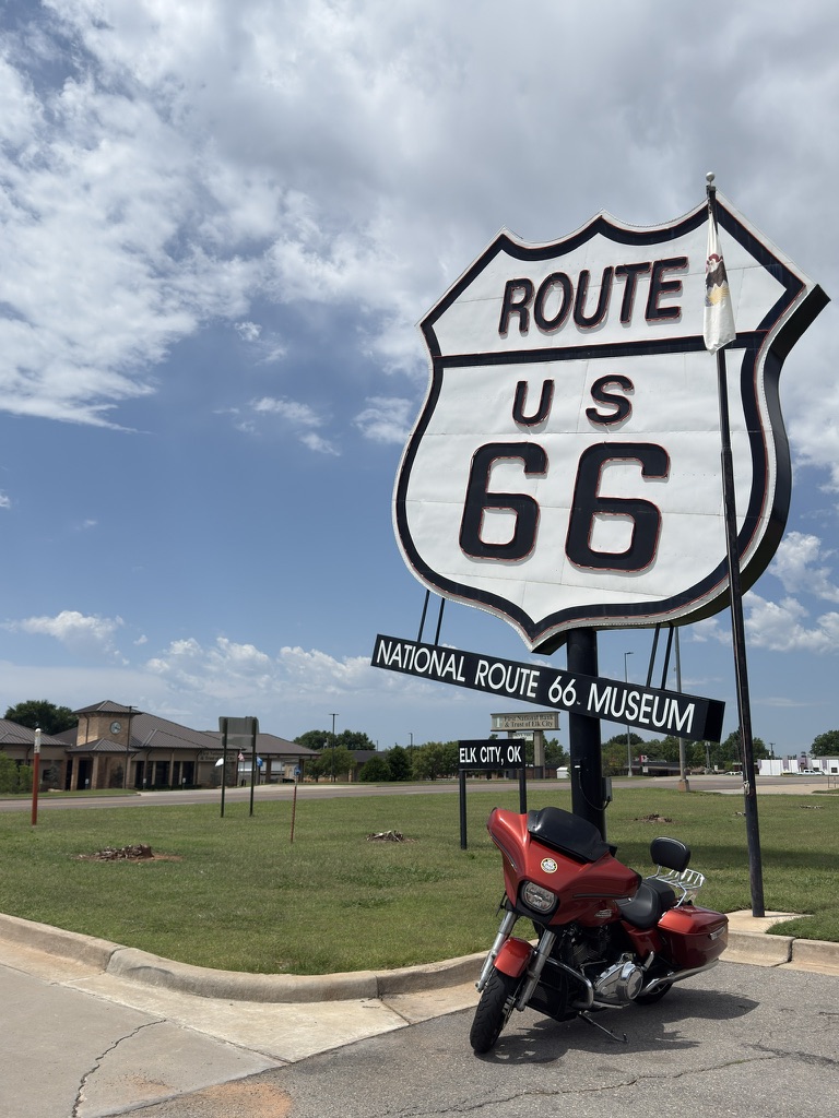 Großes Route-66-Schild mit Tafel „National Route 66 Museum, Elk City, OK“ und Motorrad davor