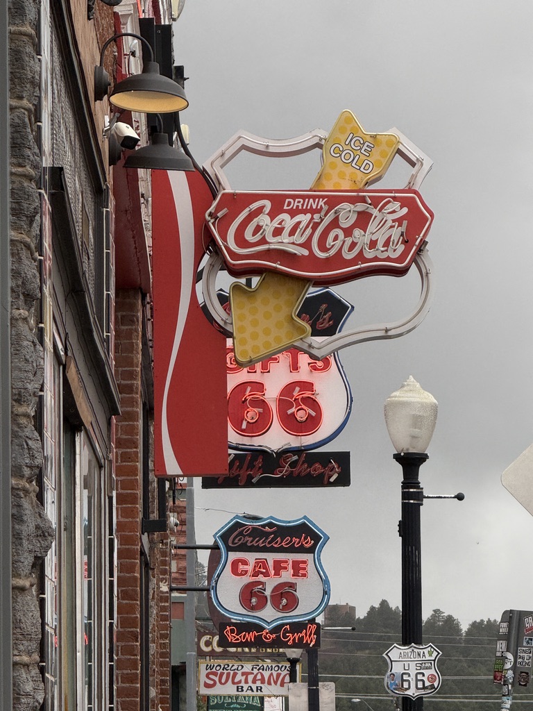 Neonschilder mit Coca-Cola-Logo und Cruisers Cafe 66 an einer Hausfassade