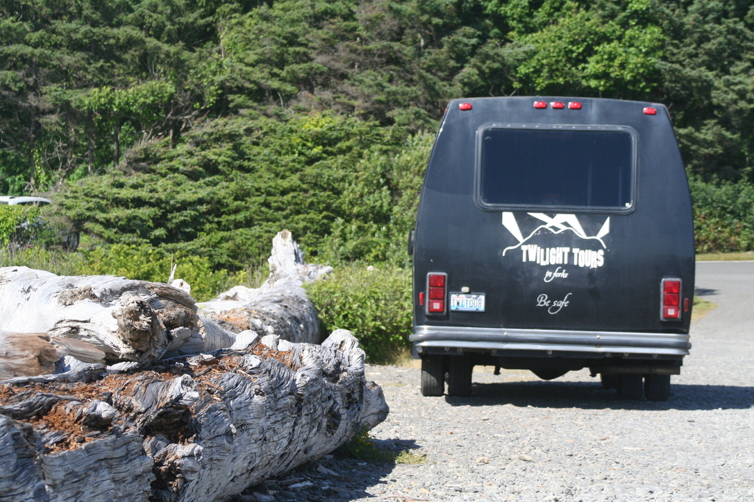 Schwarzer Kleinbus der Twilight Tours in Forks neben Treibholz