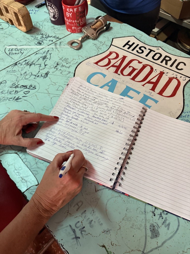 Gästebuch auf einem beschriebenen Tisch im Bagdad Café, daneben ein Historic-Bagdad-Cafe-Schild