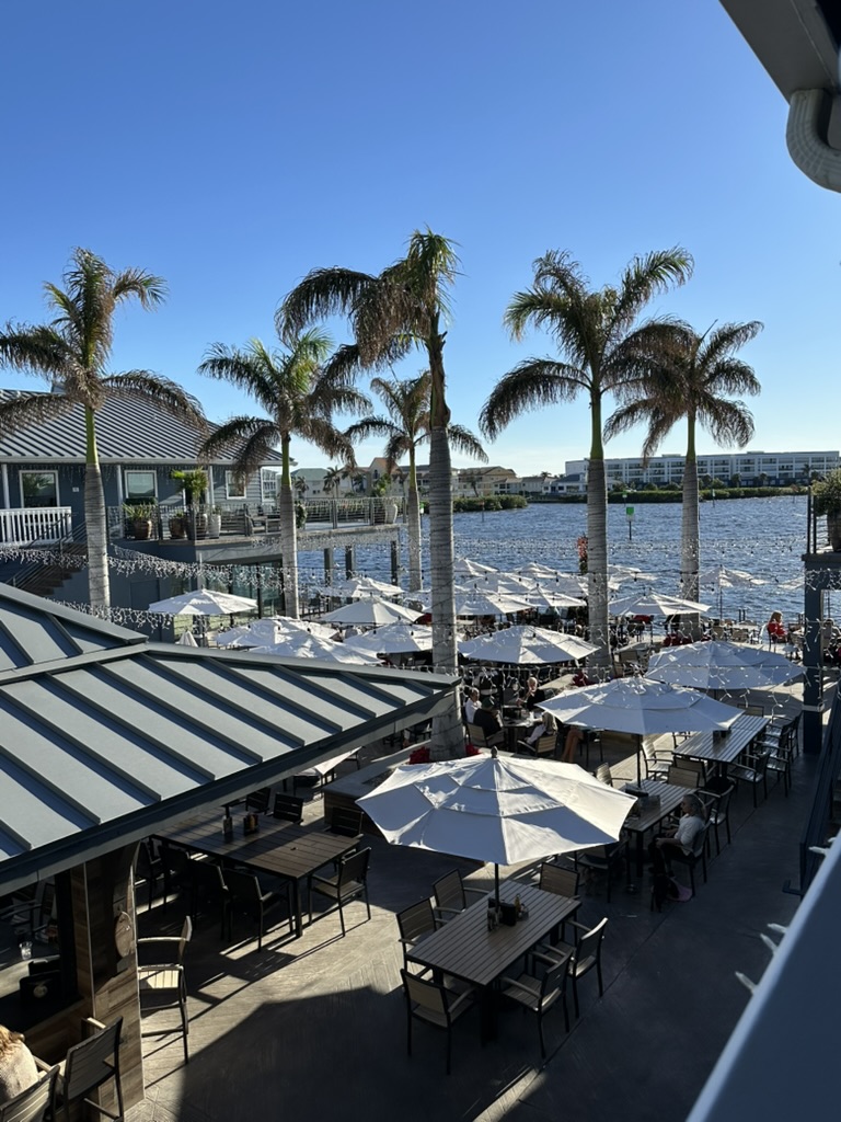 Bar mit Palmen und Tischen am Hafen