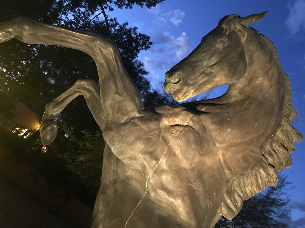 Bronzestatue eines aufsteigenden Pferdes auf der White Stallion Ranch in der Dämmerung